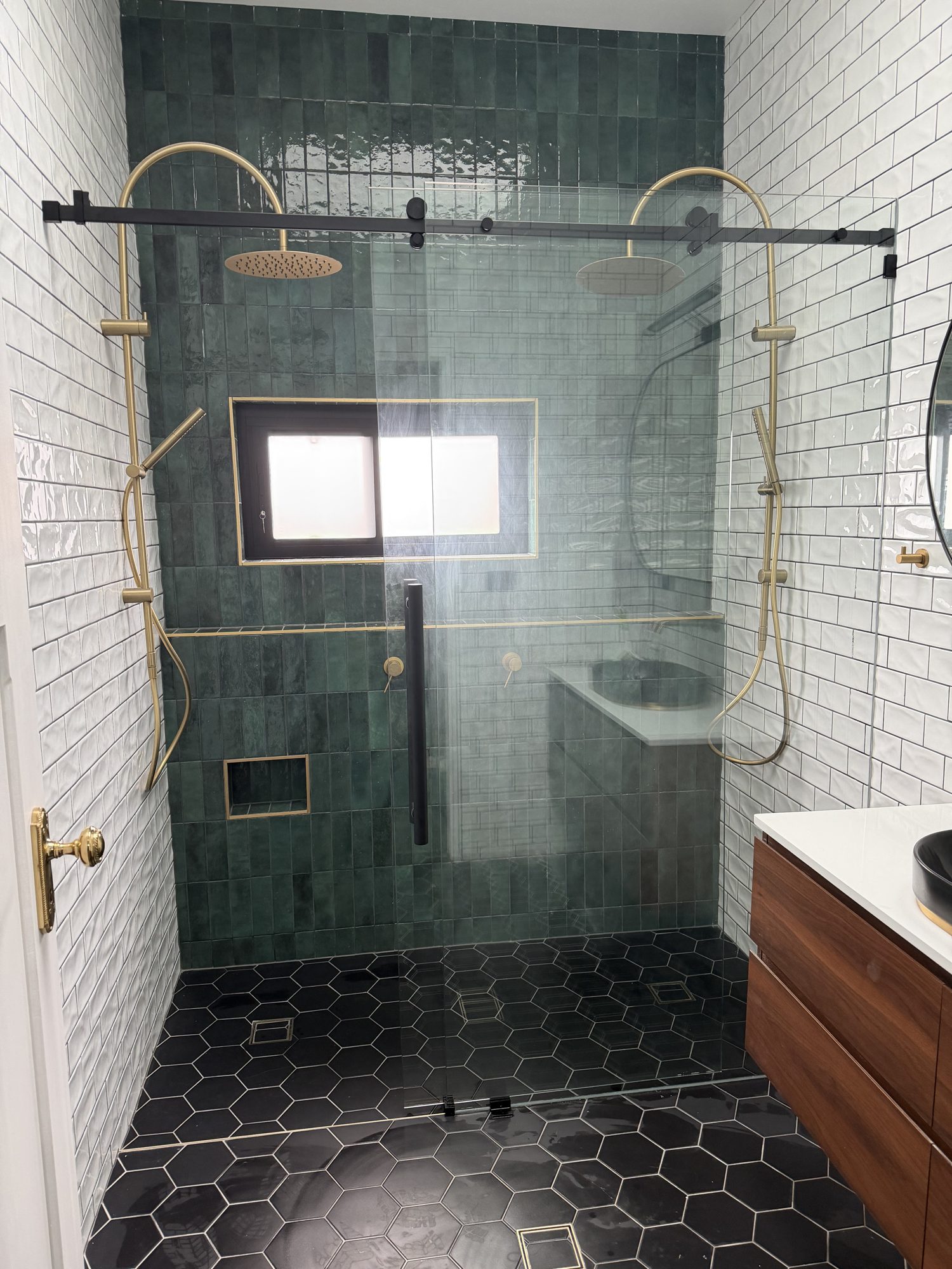 Matt black sliding shower screen against green subway tile with brushed brass tapware, Adelaide