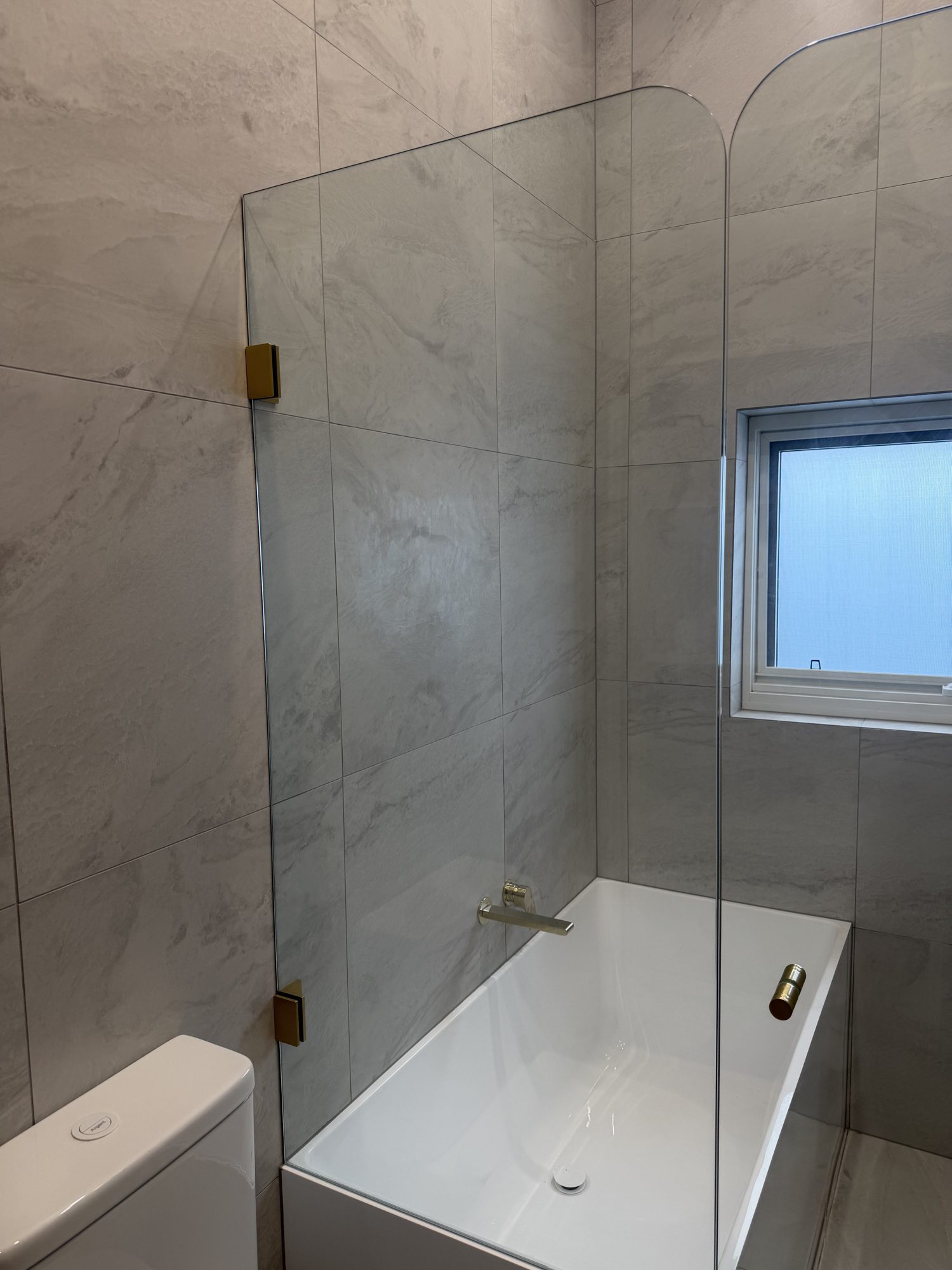 Curved-top over-bath frameless panel, brushed brass hardware, Adelaide