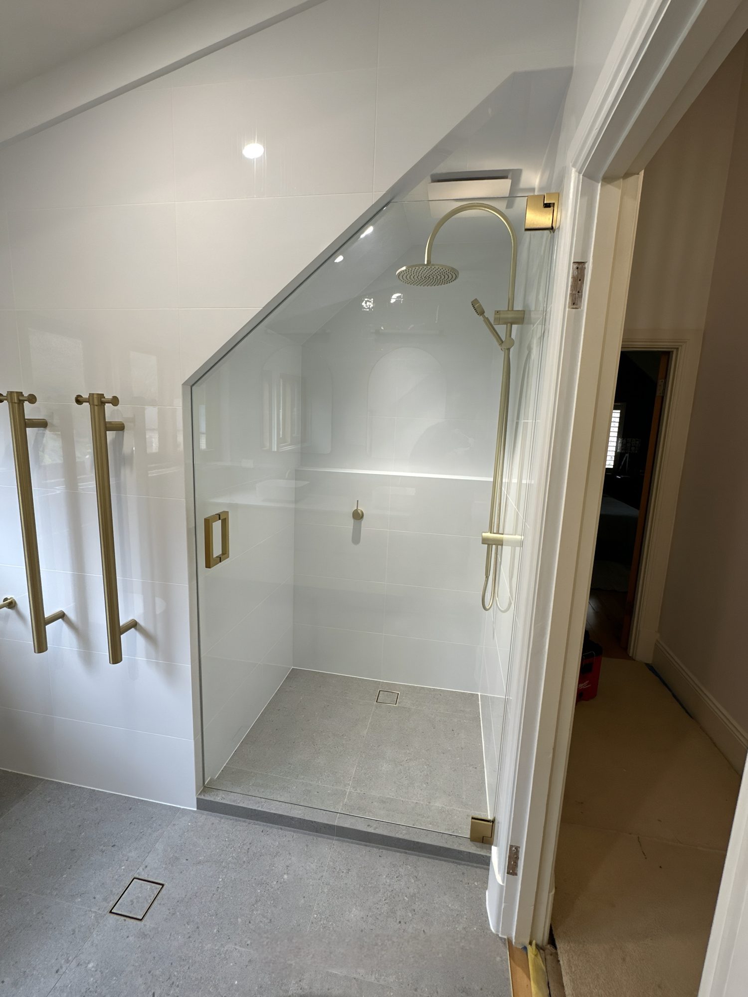 Raked-ceiling frameless shower with brushed-brass hardware, Adelaide